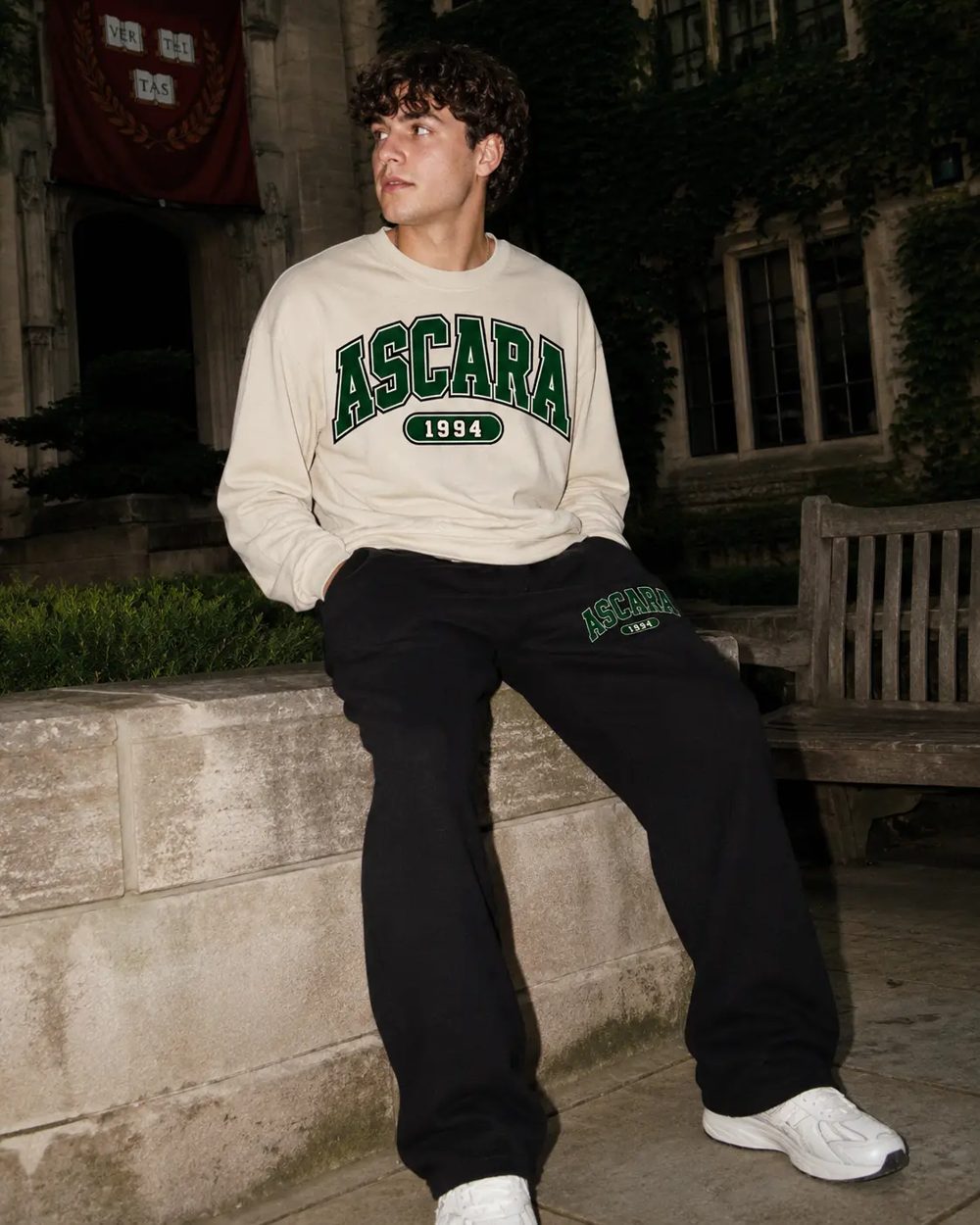Student wearing the cream Ascara crewneck and black sweatpants with green ASCARA lettering
