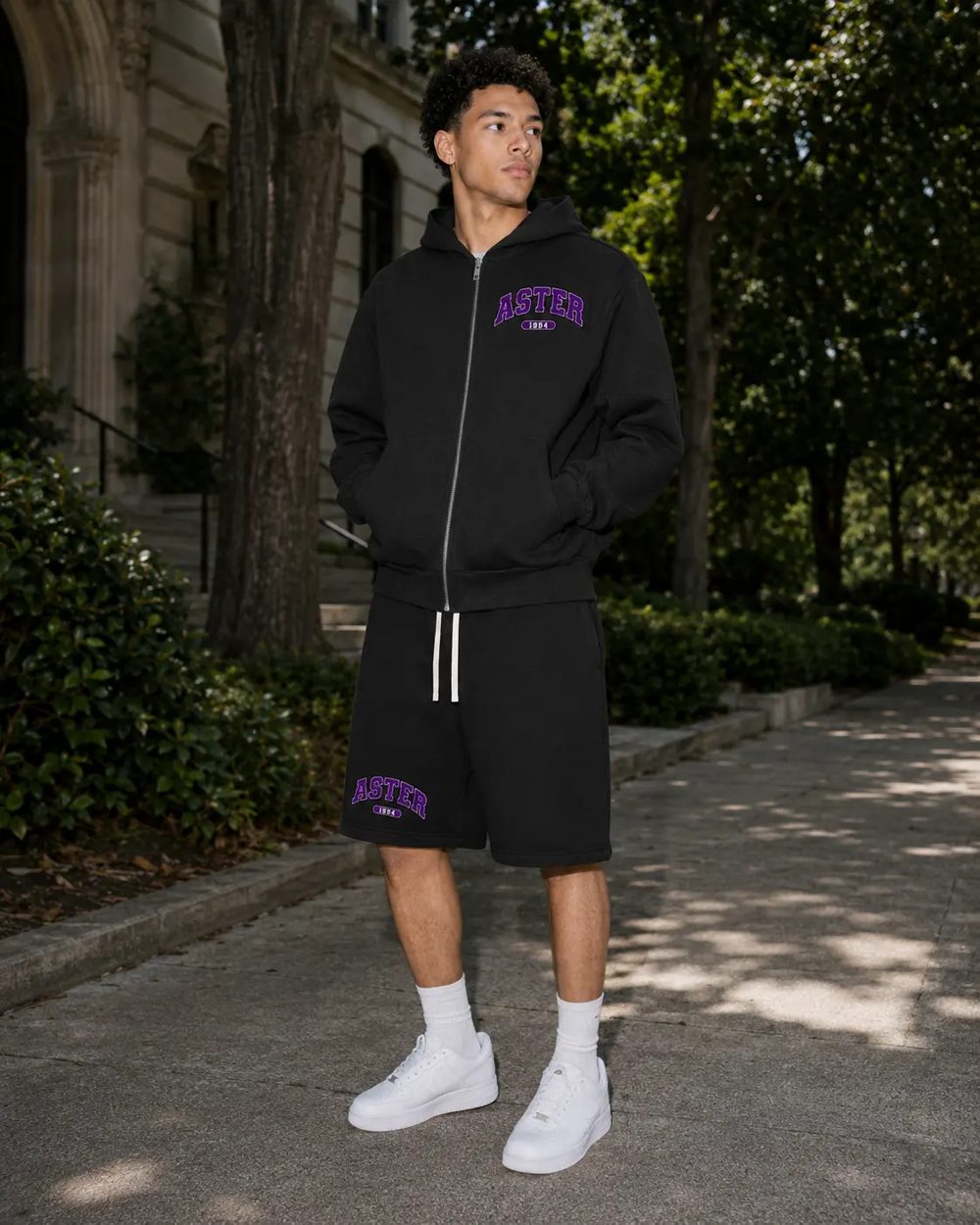 Student wearing the black Aster zip hoodie and shorts with purple ASTER varsity lettering