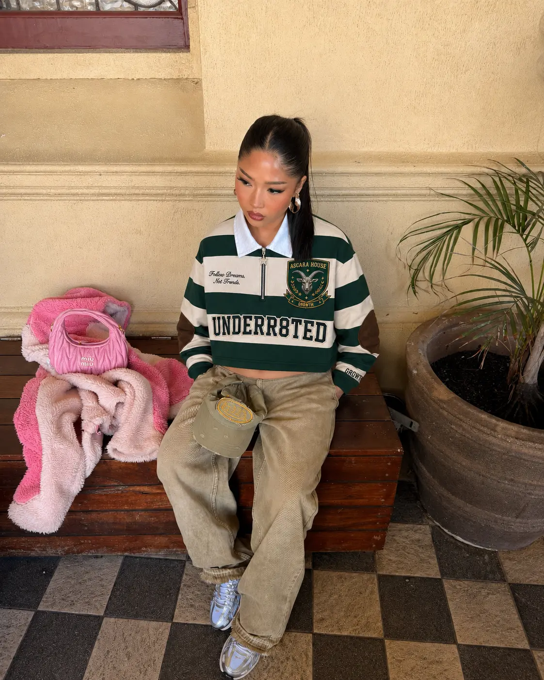 A student in a green and white Ascara rugby shirt seated on a wooden campus bench
